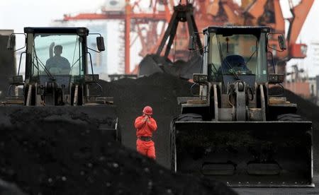 FILE PHOTO - An employee walks between front-end loaders which are used to move coal imported from North Korea at Dandong port in the Chinese border city of Dandong, Liaoning province December 7, 2010. REUTERS/Stringer/File Photo