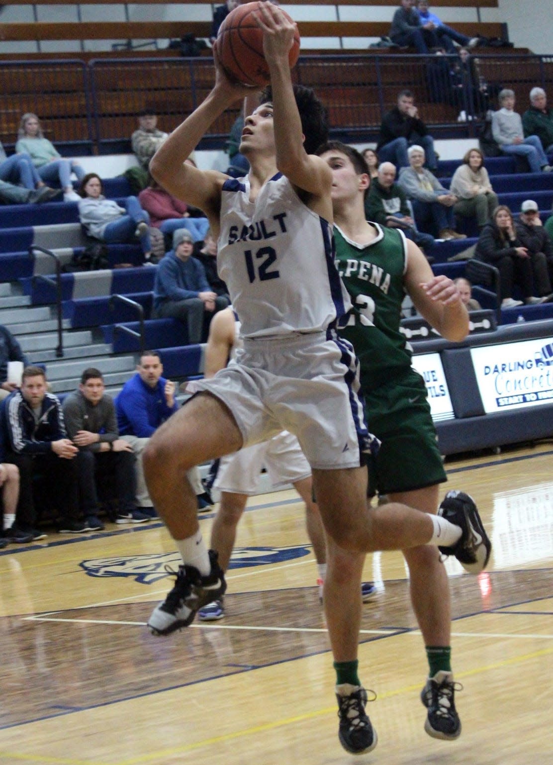 Sault Ste. Marie's Nate Koepp finishes off a drive at the basket past an Alpena defender during their matchup in the Sault Monday.