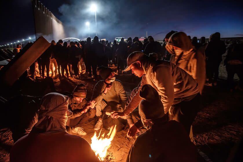 DECEMBER 17, 2022. SAN LUIS, ARIZONA. Some of the hundreds of migrants who crossed the border without authorization in the frigid early morning huddle around makeshift fires. They were guided to this location by smugglers and word of mouth on internet blogs. People from a dozen countries who were interviewed said they would make a plea for asylum. (Don Bartletti / For The Times)