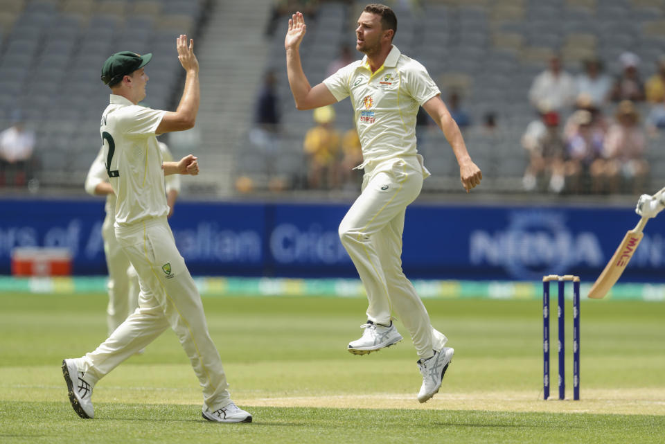 Australia's Josh Hazlewood, right, is congratulated bye teammate Cameron Green after taking the wicket of West Indies' Tagenarine Chanderpaul during play on the third day of the first cricket test between Australia and the West Indies in Perth, Australia, Friday, Dec. 2, 2022. (AP Photo/Gary Day)