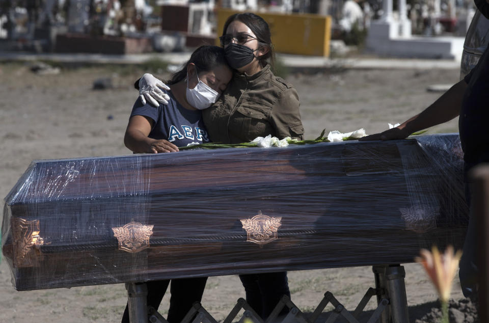 Dos mujeres se duelen en el funeral de Mauricio Ortega, de 67 años, el lunes 15 de junio de 2020 en el Cementerio Municipal de Valle de Chalco, en las afueras de la Ciudad de México. Según la familia, Ortega murió de complicaciones relacionadas con la enfermedad COVID-19. (AP Foto/Marco Ugarte)