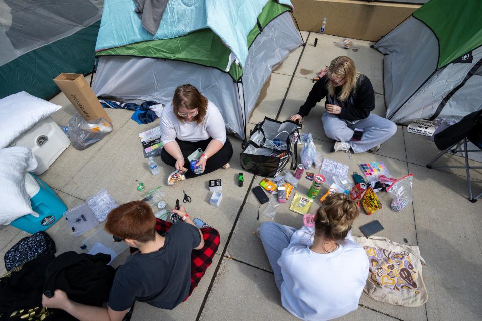 Fans shuffle through Greta Van Fleet cards while waiting in line to be be in the “pit” for their concert Monday, May 20, 2024 across the street from Fiserv Forum in Milwaukee, Wisconsin. Dozens of fans have camped out along Juneau Ave. to see the Michigan rockers on the final stop of their tour Tuesday at Fiserv Forum with the band Geese opening. The fans will wait in line until 10 a.m. Tuesday, when they will be guaranteed a spot in the pit for the show that night.