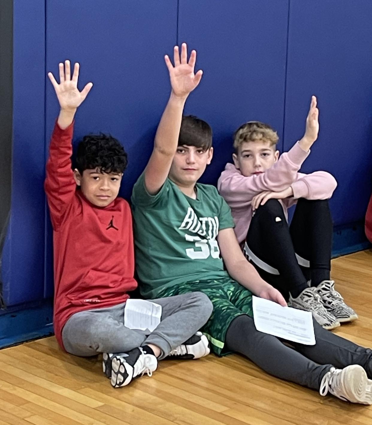 A trio of Potter Road Elementary School students raise their hands during an appearance by Daily News sports writer on March 22, 2024.