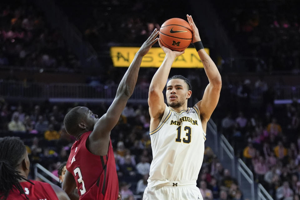 Michigan forward Olivier Nkamhoua (13) shoots on Rutgers forward Mawot Mag (3) in the second half of an NCAA college basketball game in Ann Arbor, Mich., Saturday, Feb. 3, 2024. (AP Photo/Paul Sancya)