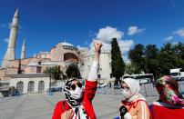 A woman gestures in front of the Hagia Sophia or Ayasofya, after a court decision that paves the way for it to be converted from a museum back into a mosque, in Istanbul