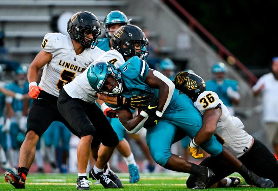 Auburn Riverside’s Jonathan Epperson (4) is brought down by a cadre of Lincoln defenders during the first half of the high school football game at Auburn Memorial Stadium, Friday, Sept. 1, 2023, Auburn, Wash.