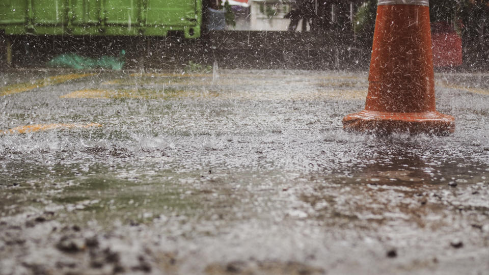 Rain falling near an orange cone.