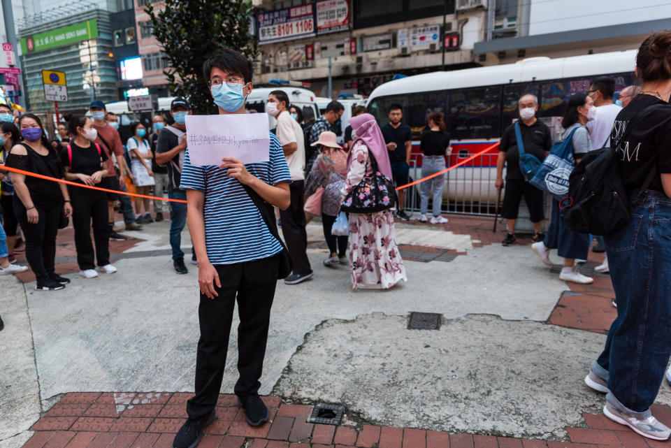 A lone protester raises a sign with the hashtag #Save12hkyouths in reference to the 12 persons arrested by Chinese coast guard as they sought to escape to Taiwan by boat in Hong Kong, China, on October 1, 2020 during the Chinese national day. (Photo by Marc Fernandes/NurPhoto via Getty Images)