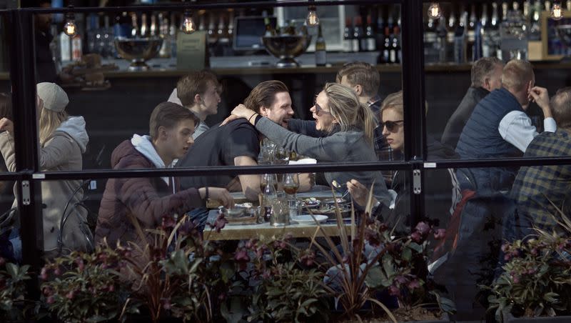 A couple hugs and laughs as they have lunch in a restaurant in Stockholm, Sweden, on Saturday, April 4, 2020. After the first confirmed virus reached Sweden in January, the Scandinavian country of 10 million opted for a different — and much-debated — approach to handling the pandemic by keeping large sections of society open.