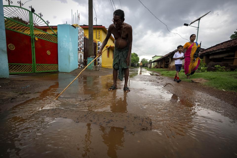 A villager moves around water on a road near a chromium ore mine at Kaliapani village in Jajpur district, Odisha, India Thursday, July 6, 2023. Kaliapani is impoverished, has barely any access to clean water and residents claim their chronic overexposure to chromium has caused lasting health problems. (AP Photo/Anupam Nath)