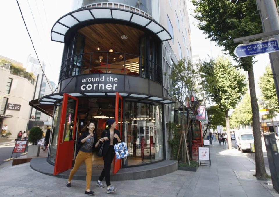 Women smile as they walk out of a shop on the Garosugil or the Tree-Lined Street in the Gangnam area of Seoul.