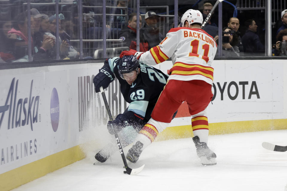 Seattle Kraken defenseman Vince Dunn (29) and Calgary Flames center Mikael Backlund (11) vie for the puck during the second period of an NHL hockey game Friday, Jan. 27, 2023, in Seattle. (AP Photo/John Froschauer)