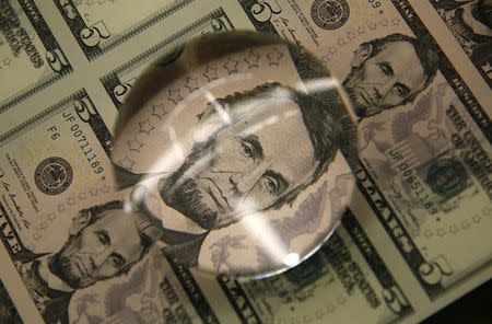 Sheets of former U.S. President Abraham Lincoln on the five-dollar bill currency are seen through a magnifying glass at the Bureau of Engraving and Printing in Washington March 26, 2015. REUTERS/Gary Cameron