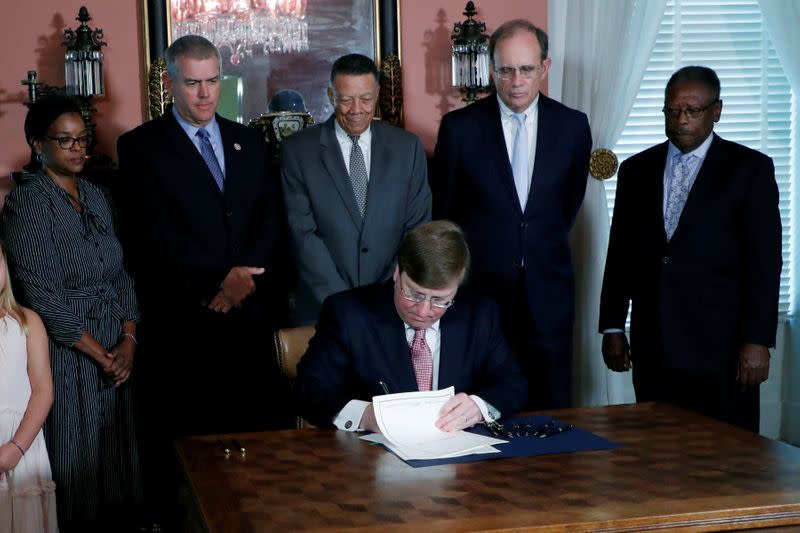 Mississippi Gov. Tate Reeves signs the bill retiring the last state flag in the United States with the Confederate battle emblem, during a ceremony at the Governor's Mansion in Jackson