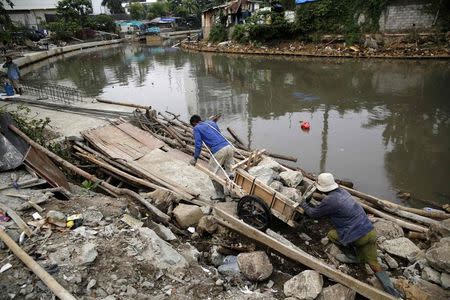 Labourers move stones to reinforce one of the city's many canals to help prevent flooding in Central Jakarta October 28, 2014. REUTERS/Darren Whiteside