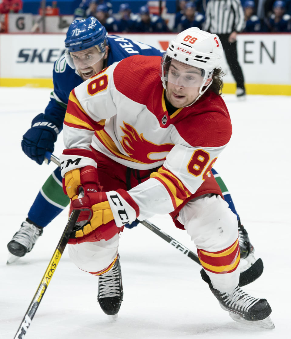 Calgary Flames left wing Andrew Mangiapane (88) vies for control of the puck with Vancouver Canucks left wing Tanner Pearson (70) during the first period of an NHL hockey game Thursday, Feb. 11, 2021, in Vancouver, British Columbia. (Jonathan Hayward/The Canadian Press via AP)