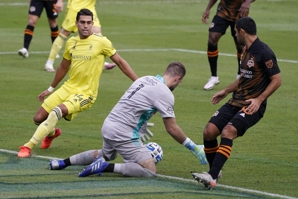 Houston Dynamo goalkeeper Marko Maric (1) makes a stop in front of Nashville forward Daniel Rios (14) during the first half of an MLS soccer match Saturday, Sept. 26, 2020, in Nashville, Tenn. (AP Photo/Mark Humphrey)