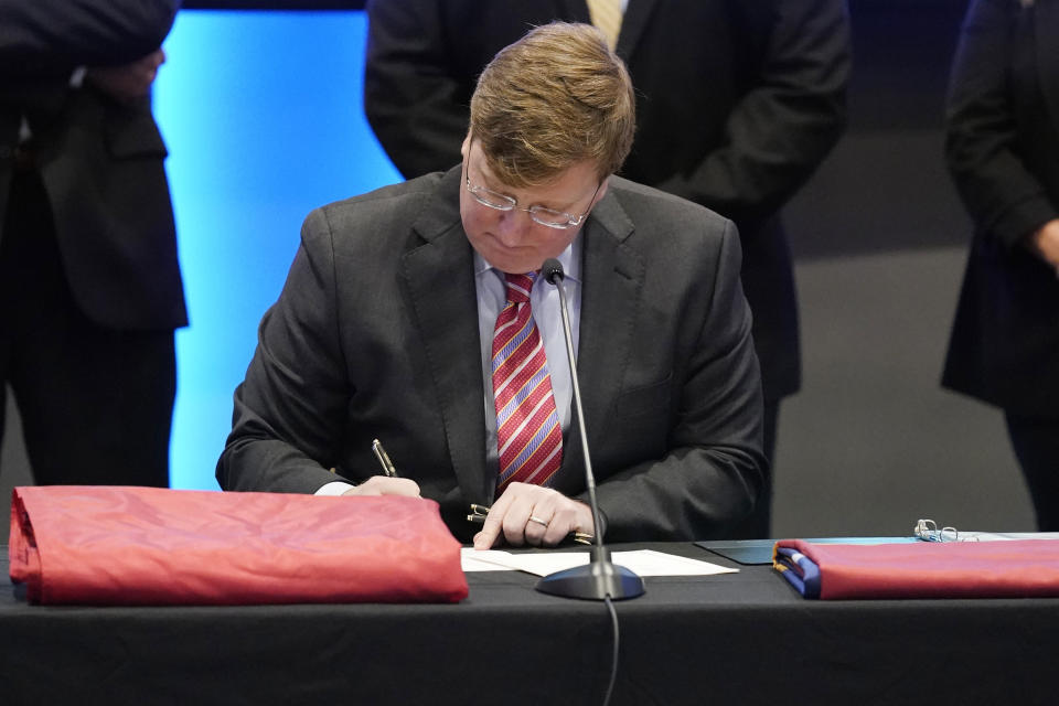 Mississippi Gov. Tate Reeves signs into law, legislation that creates the new state flag during a ceremony in Jackson, Miss., Monday, Jan. 11, 2021. The new banner features a magnolia at the center and replaces the retired flag that was the last state flag in the U.S. that included the Confederate battle emblem. (AP Photo/Rogelio V. Solis)