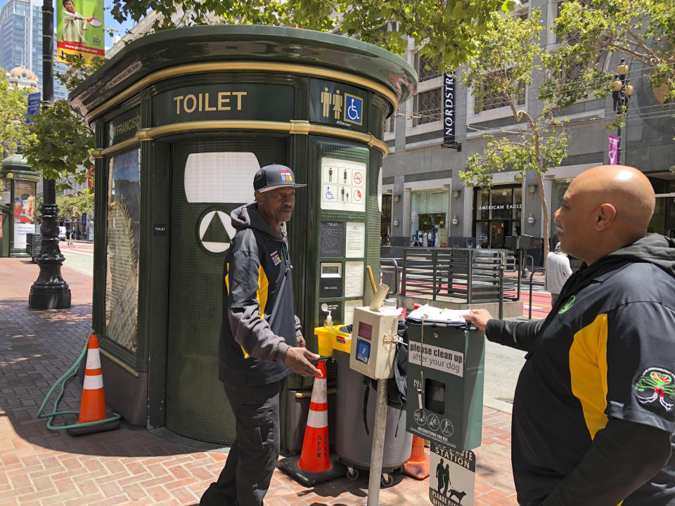 In this photo taken July 18, 2019, Nelson Butler, right, greets Lester "Smokey" Williams at one of the 25 "Pit Stop" locations in San Francisco. The program started five years ago after children complained of dodging human waste on sidewalks on their way to school. The "Pit Stop" program employs recently released inmates, like Butler and Williams, to keep the bathrooms secure and clean. (AP Photo/Janie Har)