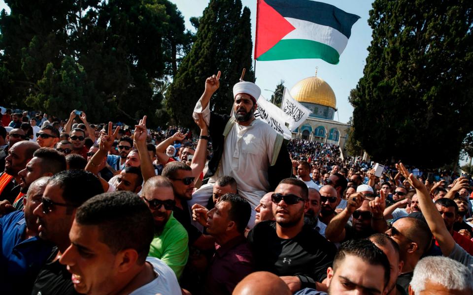 Palestinians carry the director of Al-Aqsa mosque, Sheikh Omar Kiswani, on their shoulders - Credit: AHMAD GHARABLI/AFP/Getty Images