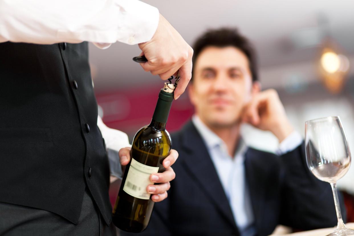 waiter serving wine to a customer at the restaurant