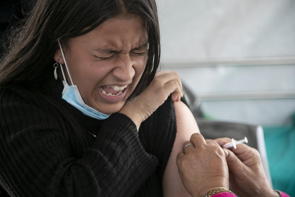 FILE - A girl reacts as she receives a shot of the Pfizer-BioNTech vaccine for COVID-19 in Kathmandu, Nepal, Tuesday, Nov. 23, 2021. Children above the age of 12 are now receiving the vaccine in Nepal. The World Health Organization downgraded its assessment of the coronavirus pandemic on Friday, May 5, 2023, saying it no longer qualifies as a global emergency. (AP Photo/Niranjan Shrestha, File)