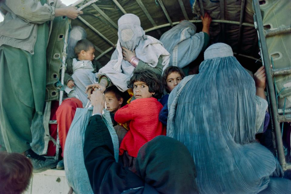 Women in children pack into the back of a truck.