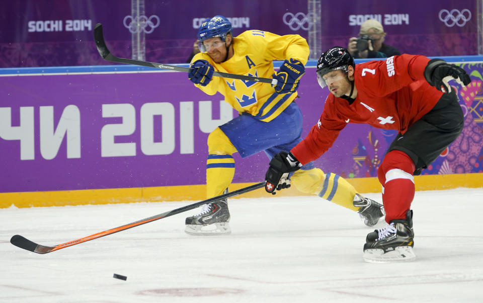 Sweden forward Daniel Alfredsson takes a shot against Switzerland defenseman Mark Streit in the first period of a men's ice hockey game at the 2014 Winter Olympics, Friday, Feb. 14, 2014, in Sochi, Russia. (AP Photo/Mark Humphrey)