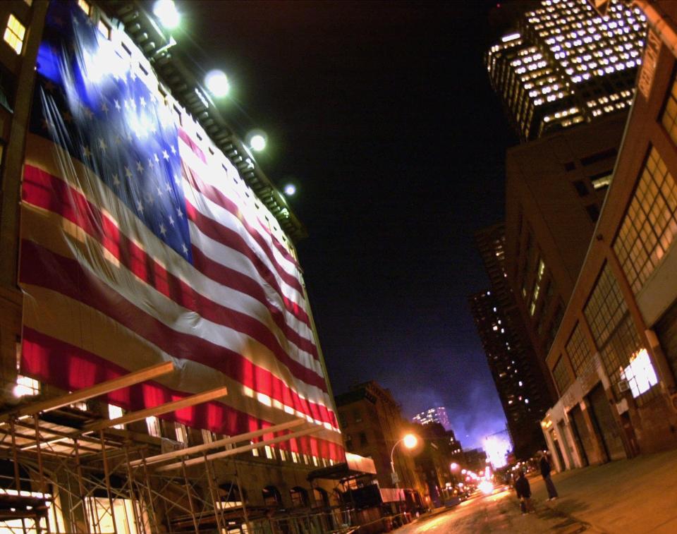 A large flag drapes a building several blocks north of the smoldering World Trade Center site in New York early Thursday morning, Sept. 27, 2001. Work continues around the clock clearing the site which was destroyed in terrorist attacks Sept. 11.