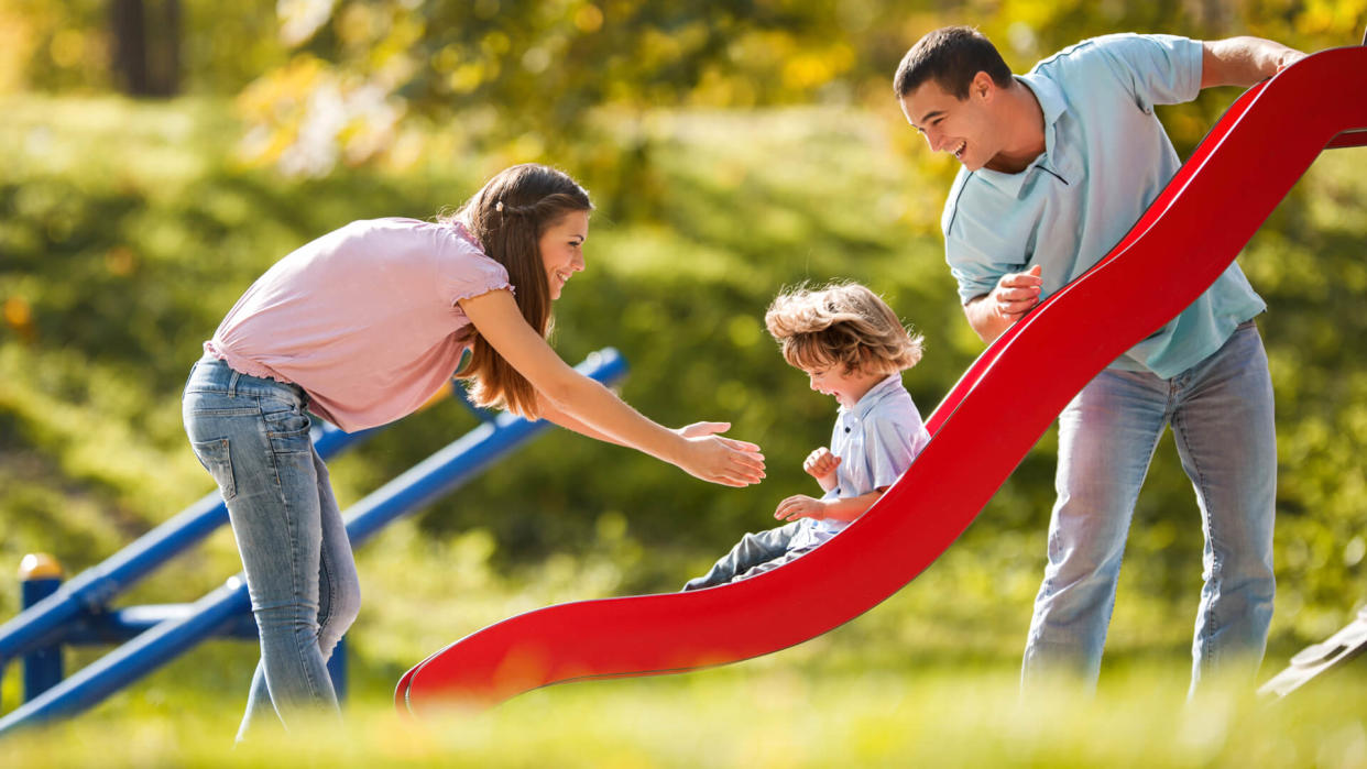 Cheerful parents having fun with their son in the playground.