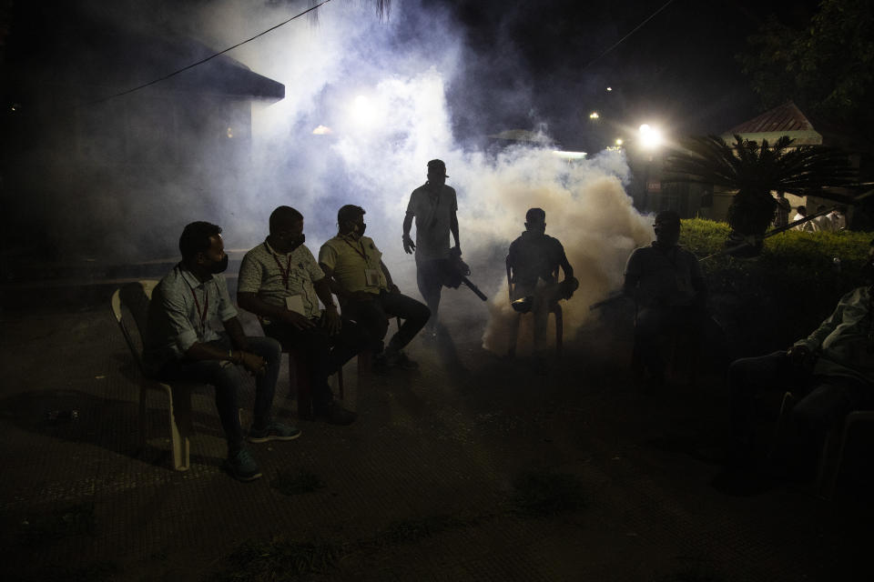 A municipal worker fumigates as supporters of Bharatiya Janata Party wait outside a vote counting center in Gauhati, India, Sunday, May 2, 2021. Preliminary voting trends released by India's electoral body on Sunday indicate Prime Minister Narendra Modi’s Hindu nationalist party failed to make gains in four recent state elections, a sign his political strength may be slipping as the country struggles to contain an unprecedented surge in coronavirus cases. (AP Photo/Anupam Nath)