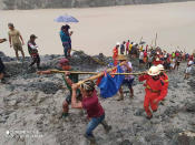 In this photo released from Myanmar Fire Service Department, rescuers carry a recovered body of a victim in a landslide from a jade mining area in Hpakant, Kachin state, northern Myanmar Thursday, July 2, 2020. Myanmar government says a landslide at a jade mine has killed dozens of people. (Myanmar Fire Service Department via AP)