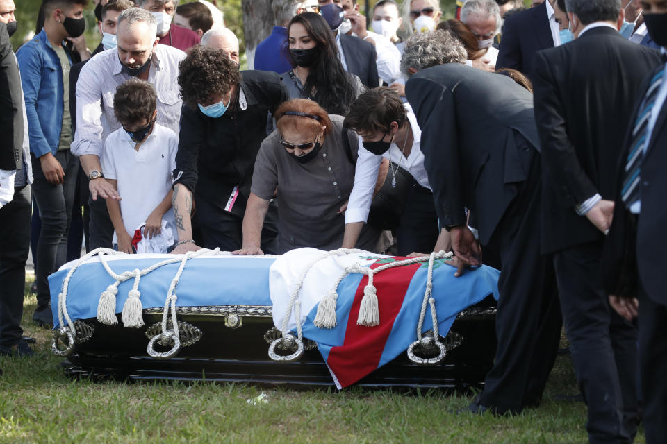 La familia del expresidente argentino Carlos Menem toca el ataúd durante su funeral en el Cementerio Islámico de San Justo, Argentina, el lunes 15 de febrero de 2021. El exmandatario peronista, que gobernó durante diez años el país sudamericano, falleció la víspera a los 90 años. (AP Foto/Natacha Pisarenko)