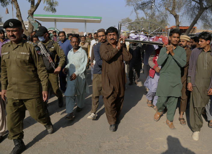 Police officers escort relatives carrying the body of Mushtaq Ahmed, 41, who was killed when an enraged mob stoned him to death for allegedly desecrating the Quran, during his funeral in Tulamba, a remote village in the district of Khanewal in eastern Pakistan, Sunday, Feb. 13, 2022. Mob attacks on people accused of blasphemy are common in this conservative Islamic nation where blasphemy is punishable by death. (AP Photo/Asim Tanveer)