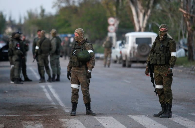 Los miembros de las tropas prorrusas hacen guardia en una carretera antes de la esperada evacuación de los soldados ucranianos heridos de la acería Azovstal, en Mariúpol, Ucrania