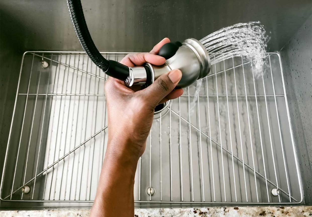 Close up of a hand rinsing kitchen sink