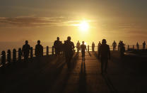 FILE- In this file photo taken Monday May 18, 2020, people exercise along the promenade at sunrise in Sea Point, Cape Town, South Africa, as the country marked day 53 of a strict government lockdown in a bid to prevent the spread of coronavirus. South Africa is struggling to balance its fight against the coronavirus with its dire need to resume economic activity. The country with the Africa’s most developed economy also has its highest number of infections — more than 19,000. (AP Photo/Nardus Engelbrecht, file)