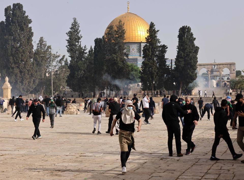 Palestinians run for cover from tear gas fired by Israeli security forces at Jerusalem’s Al-Aqsa mosqueAFP via Getty Images