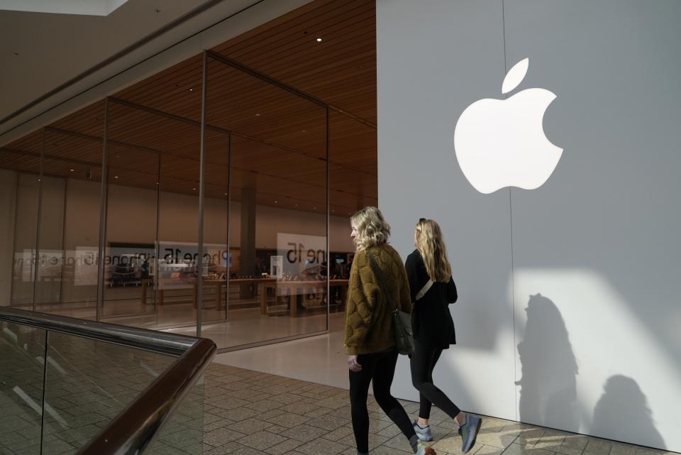 FILE - People walk by an Apple store Oct. 20, 2023, in Denver. The U.S. Justice Department's double-barreled antitrust attack on Google's dominant search and Apple's trendsetting iPhone is reviving memories of another epic battle that hobbled Microsoft before it roared back to yet again become the world's most valuable company. (AP Photo/Brittany Peterson, File)