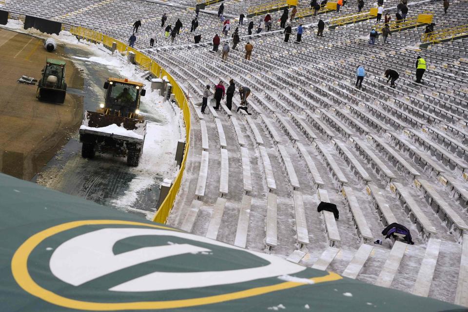 Shovelers clear snow between bleachers at Lambeau Field in Green Bay, Wisconsin, the home field of the Green Bay Packers of the National Football League (NFL), December 21, 2013. In winter months, the team calls on the help of hundreds of citizens, who also get paid a $10 per-hour wage, to shovel snow and ice from the seating area ahead of games, local media reported. The Packers will host the Pittsburgh Steelers on Sunday, December 22. REUTERS/Mark Kauzlarich (UNITED STATES - Tags: ENVIRONMENT SPORT FOOTBALL)