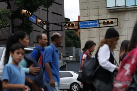 People walk next to a non-functioning traffic light during a blackout in Caracas