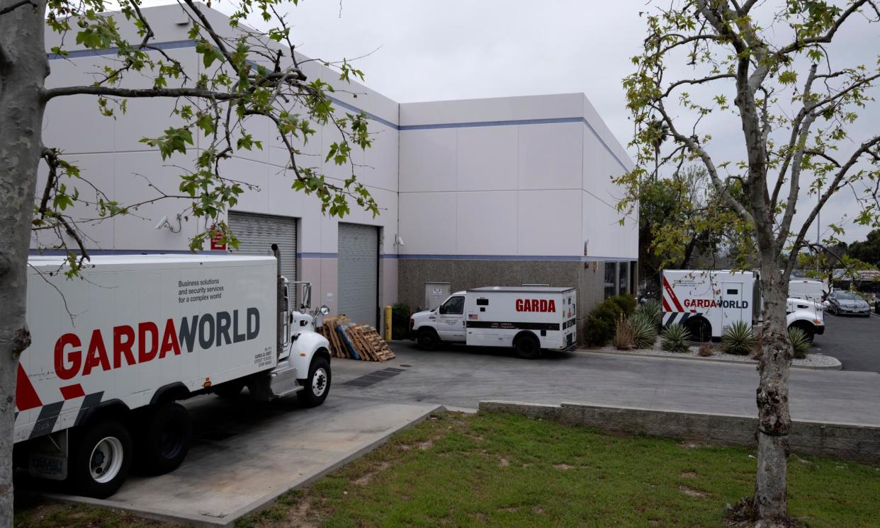 <span>Armored trucks are parked outside the GardaWorld facility in the Sylmar section of Los Angeles on Thursday. Thieves stole as much $30m in a burglary.</span><span>Photograph: Richard Vogel/AP</span>