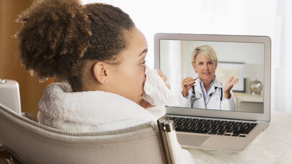 Sick woman video chatting with doctor on laptop