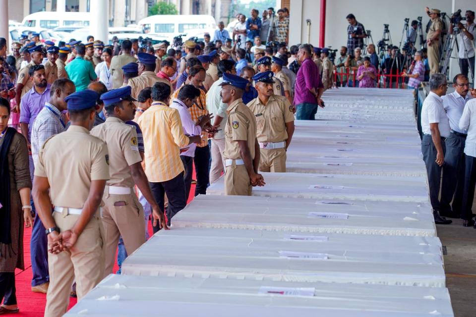 Policemen stand guard as mourning relatives wait for coffins of Indian workers killed in the Kuwait fire to arrive in Kochi (AFP via Getty)