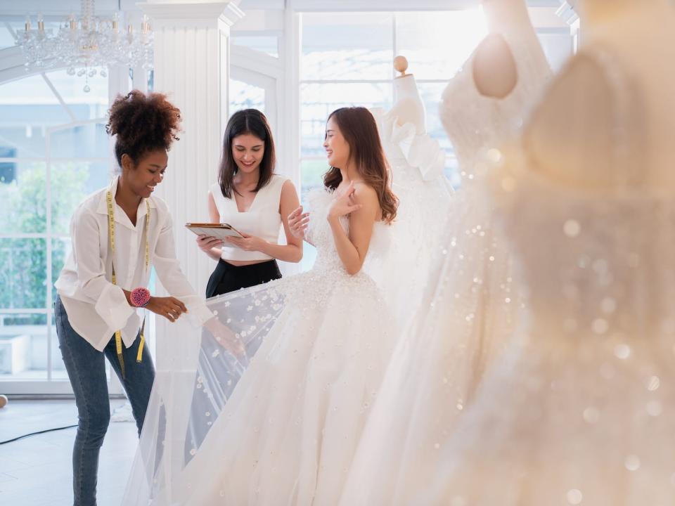 Two consultants help a bride with a wedding dress.