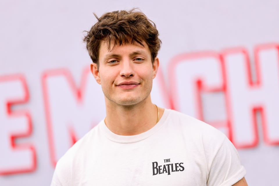 Matt Rife smiling with short hair, wearing a T-shirt with "The Beatles" text, in front of a blurred backdrop