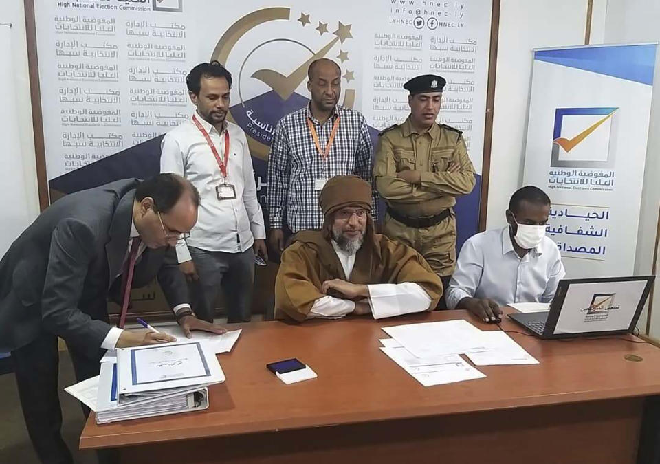 Seif al-Islam, center, the son and one-time heir apparent of late Libyan dictator Moammar Gadhafi registers his candidacy for the country’s presidential elections next month, in Sabha, Libya, Sunday, Nov. 14, 2021. Al-Islam, who was seen as the reformist face of Gadhafi's regime before the 2011 uprising, was released in June 2017 after more than five years of detention. (Libyan High National Elections Commission via AP)