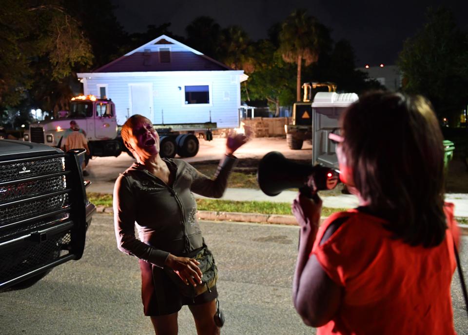 Branda Watty, left, and Vickie Oldham, both with Newtown Alive, sing gospel songs as workers begin moving the historic Leonard Reid House early Friday morning.