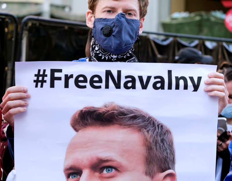 FILE PHOTO: A protester wearing a face mask holds a poster of Alexei Navalny in Hollywood during a demonstration in support of Russian opposition leader Alexei Navalny,