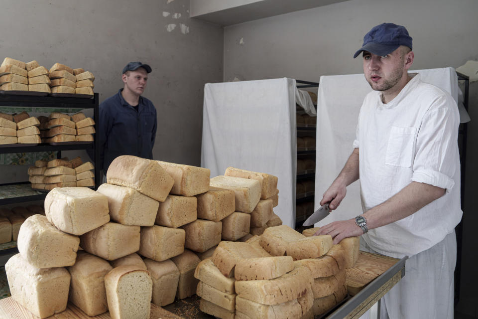 Russian prisoner of war Alexander, 26, right, slices bread in the kitchen of a detention center in Ukraine's Lviv region, Thursday, April 25, 2024. AP visited the center as part of a small group of journalists on the condition that its exact location be withheld and spoke with Russian POWs, who gave only their first names. (AP Photo/Evgeniy Maloletka)